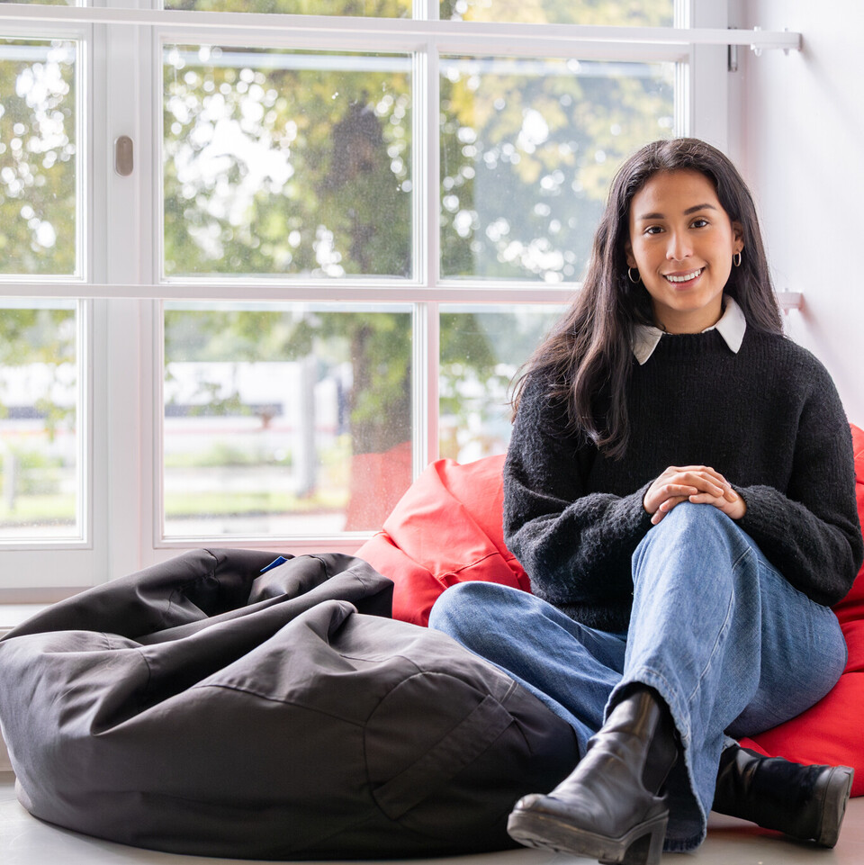 Studentin sitzt auf einem Sitzkissen vor einem Fenster