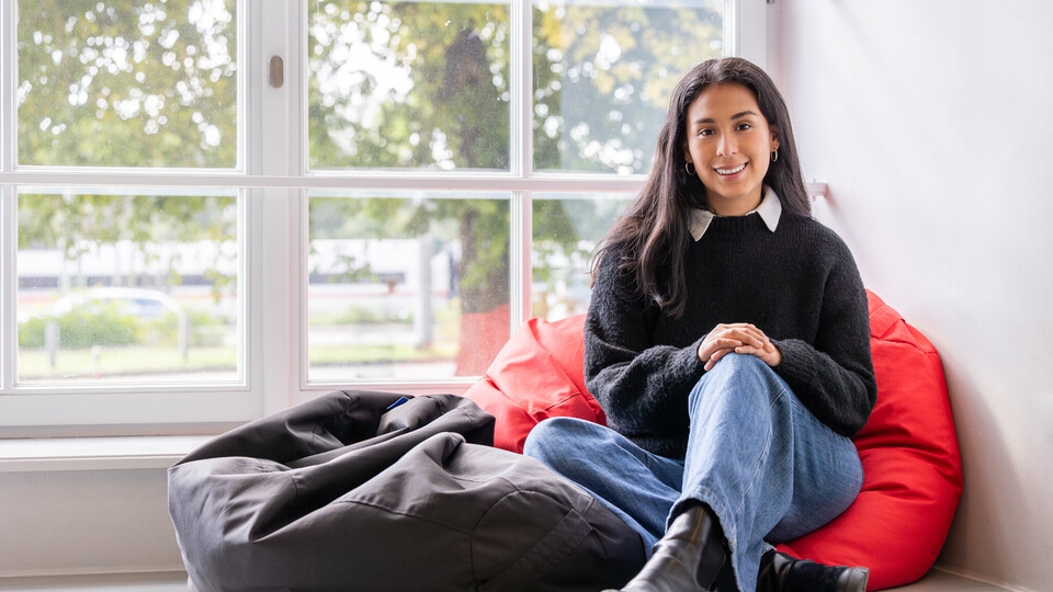 Studentin sitzt auf einem Sitzkissen vor einem Fenster
