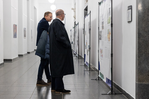 Zwei Personen stehen vor mehreren Austellungstafeln bei einer Vernissage