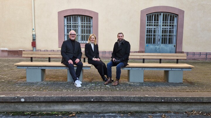 Thomas Gleßner, Sabrina Scherbarth und Christian Haas sitzen auf den neuen Sitzbänken im Schneckenhof.