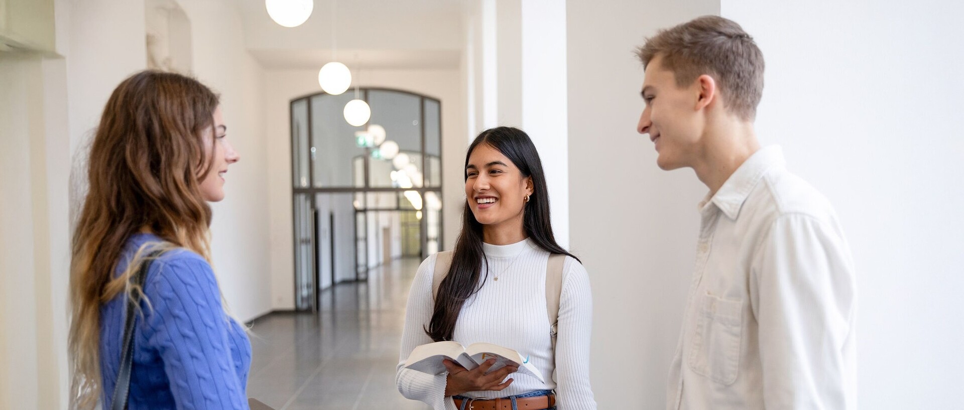 Drei Studierende stehen auf einem Flur im Mannheimer Schloss und unterhalten sich.