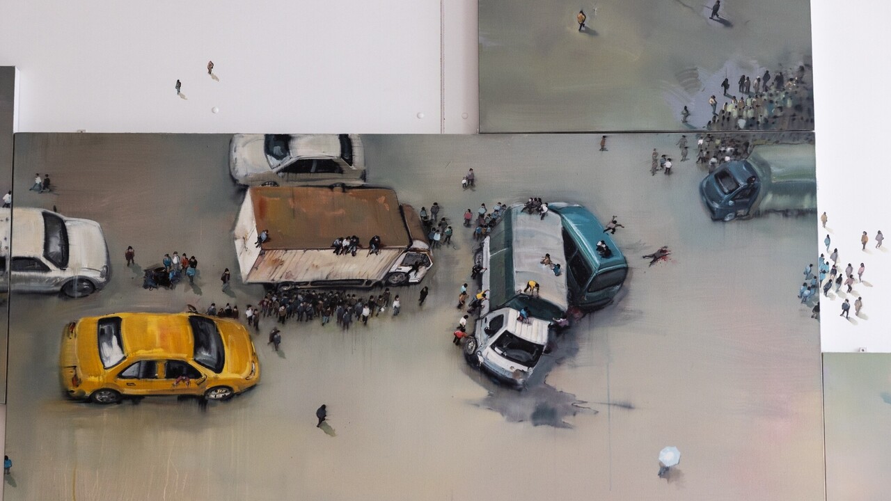 Gemälde einer Person mit Miniaturfiguren, das sich auf die Wand fortsetzt. An einer Stelle sind Autos, Figuren und ein Verkehrschaos mit Unfall dargestellt.