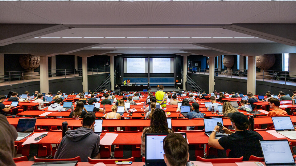 Blick von hinten in einen Hörsaal während einer digitalen Prüfung: Studierende sitzen an ihren eigenen Laptops, konzentriert und mit Abstand verteilt – moderne Prüfungsform im Einsatz