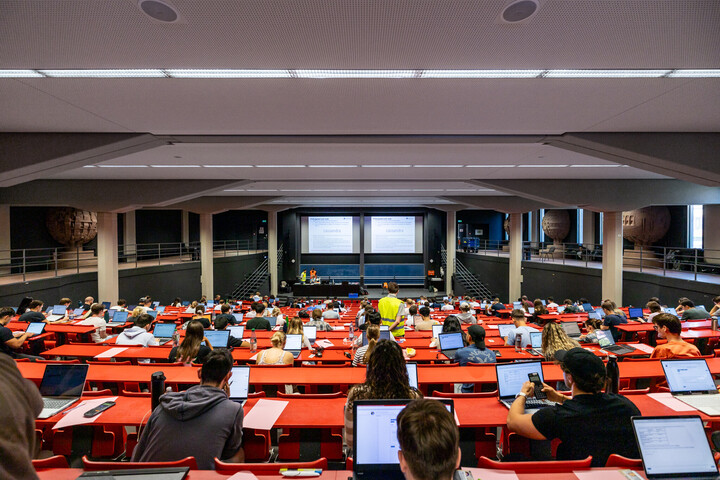 Blick von hinten in einen Hörsaal während einer digitalen Prüfung: Studierende sitzen an ihren eigenen Laptops, konzentriert und mit Abstand verteilt – moderne Prüfungsform im Einsatz