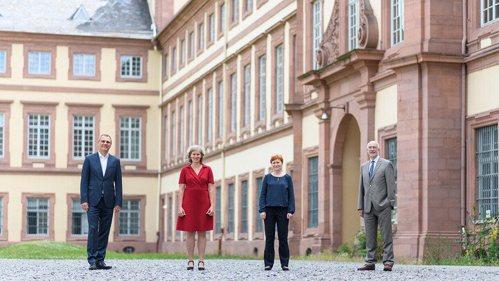 Vier Personen stehen vor dem Mannheimer Schloss.