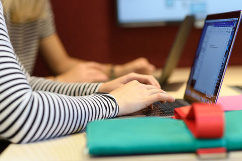 Zwei Studierende sitzen vor ihren Laptops.