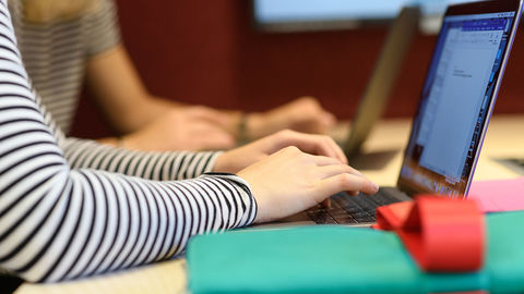 Zwei Studierende sitzen vor ihren Laptops.