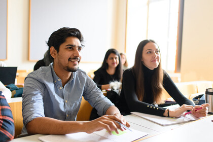 Eine Studentin und ein Student hören begeistert bei einem Vortrag zu.
