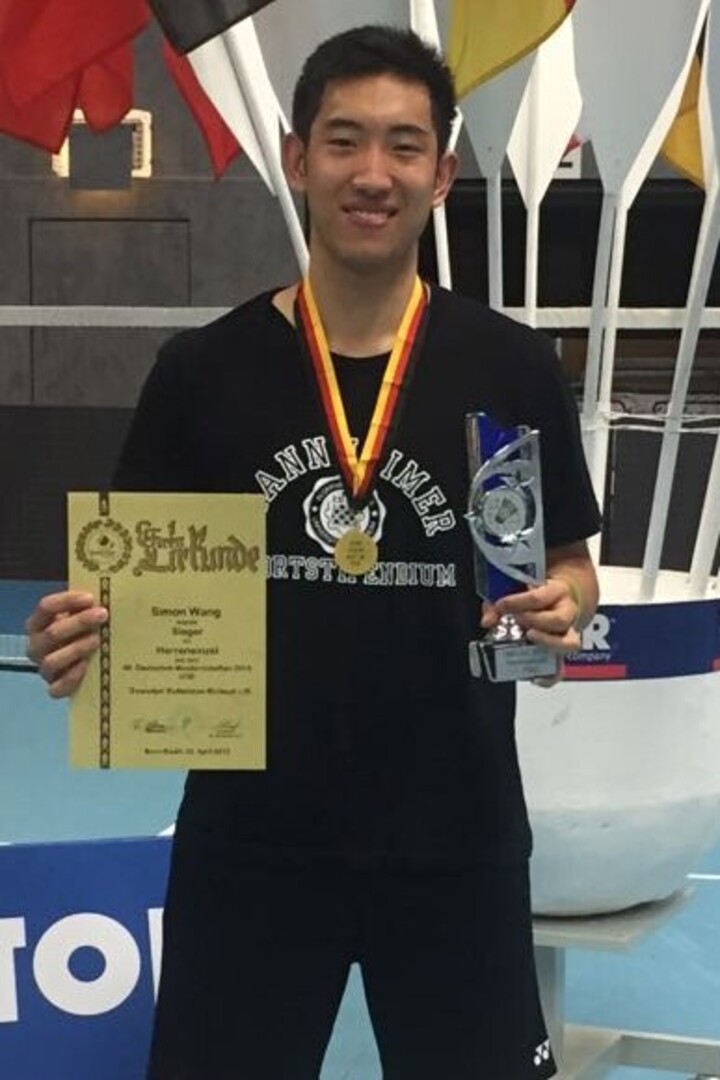 Ein Sportler mit Urkunde, Medaille und Trophäe in der Sporthalle