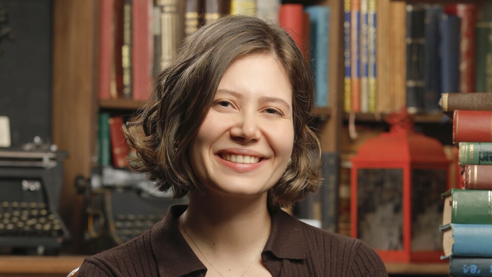Hilal Tanyas in front of a shelf full of books