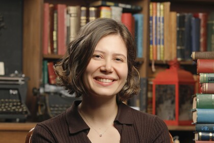 Hilal Tanyas in front of a shelf full of books