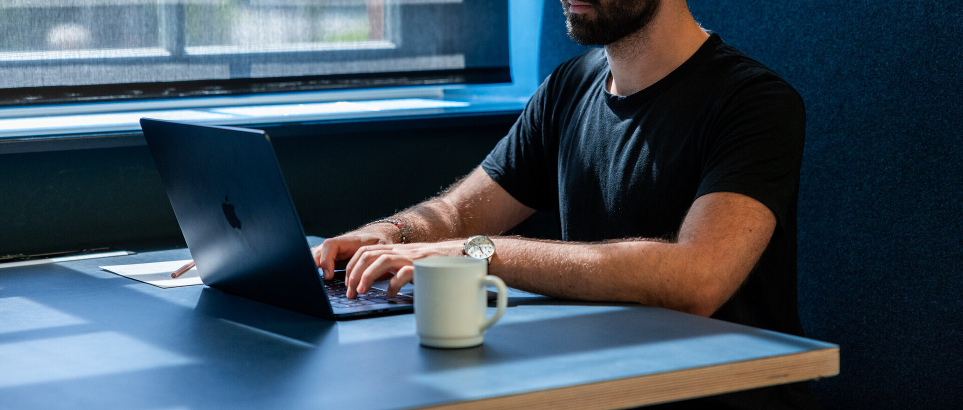 Studierender arbeitet mit Laptop an einem Tisch 