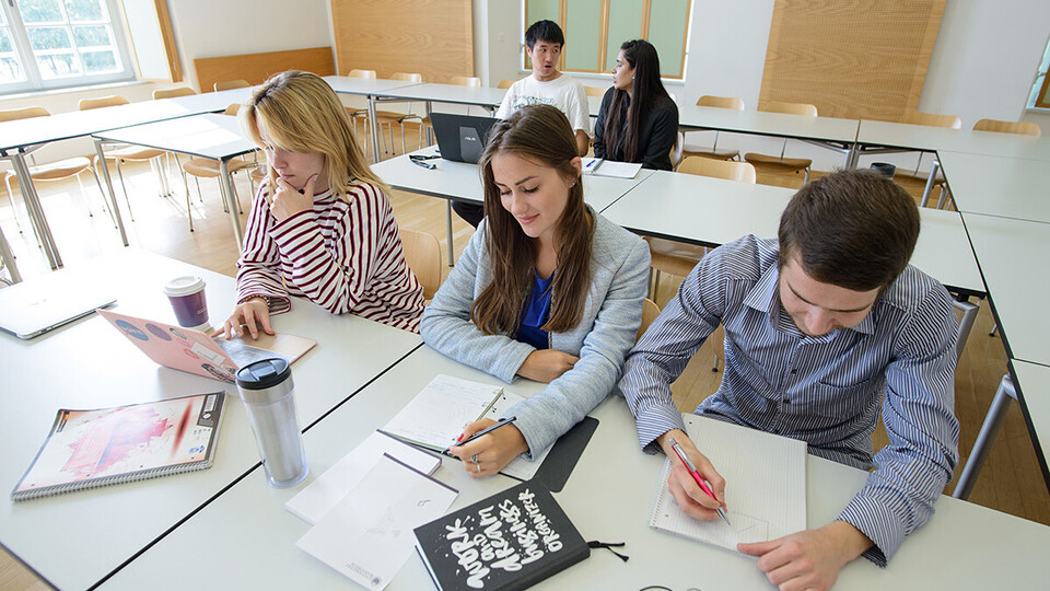 Fünf Studierende sitzen in einem Seminarraum.