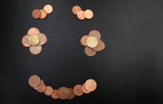 Ein Lachendes Gesicht mit Augen, Augenbrauen und Mund aus Geldmünzen gelegt