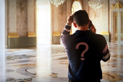 Ein Mann telefoniert und hält die andere Hand nachdenklich an den Kopf. Er ist von hinten zu sehen und trägt ein großes Fragezeichen auf seinem Pullover.