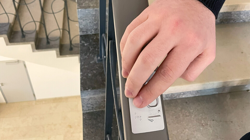Hand berührt Braille-Einkerbung im EO-Treppenhaus