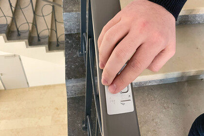 Hand berührt Braille-Einkerbung im EO-Treppenhaus