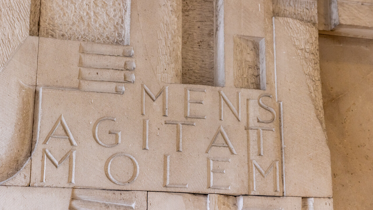 In eine Steinmauer ist der lateinische Ausdruck "Mens Agitat Molem" eingemeißelt.