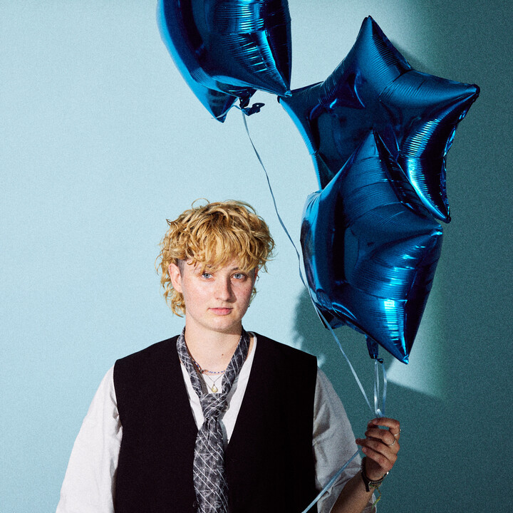 Eine Person hält mehrere Luftballons in den Händen.