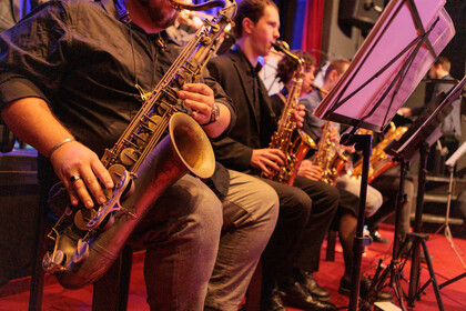 Vier Saxofonisten sitzen nebeneinander, im Fokus des Bildes ist das Instrument eines Spielers.