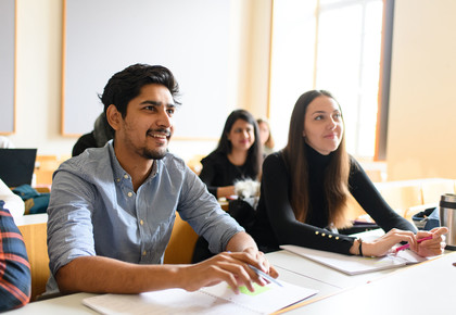 Eine Studentin und ein Student hören begeistert bei einem Vortrag zu.