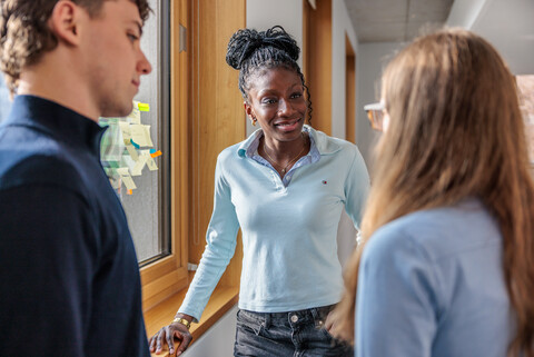 Zwei Studentinnen und ein Student unterhalten sich. 