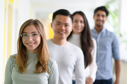 Mehrere Studierende stehen hintereinander aufgereiht und lächeln.