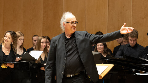 Ein Dirigent mit seinem schwarz gekleideten Chor während eines Auftritts.