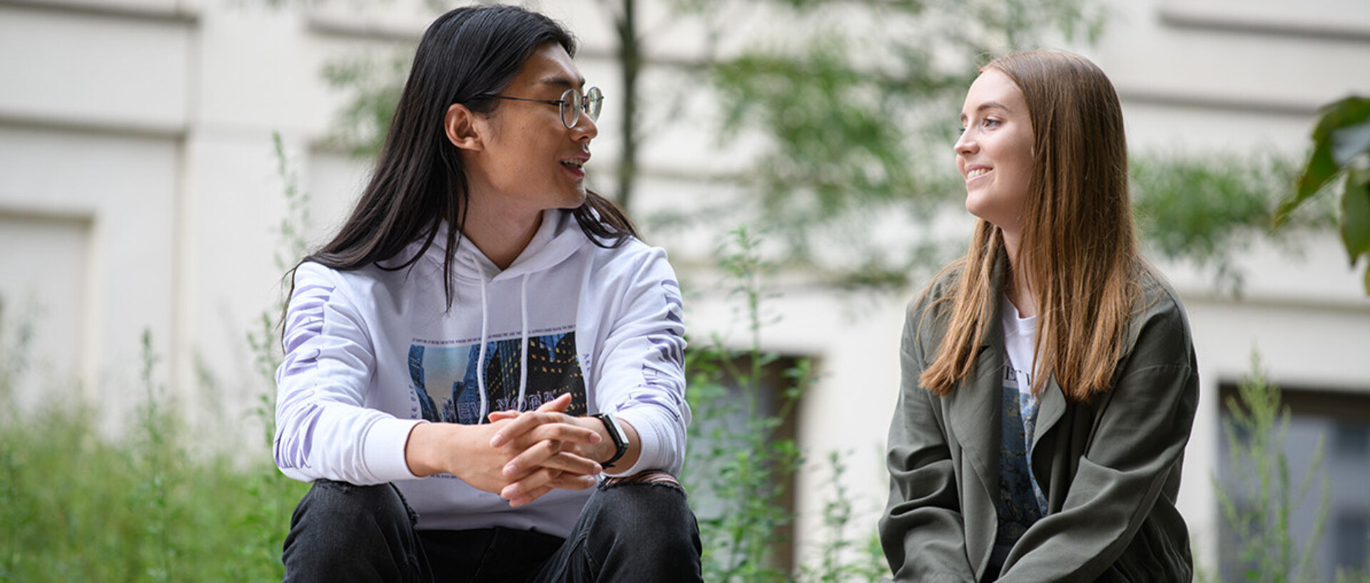 Zwei Studierende unterhalten sich draußen auf dem Campus.