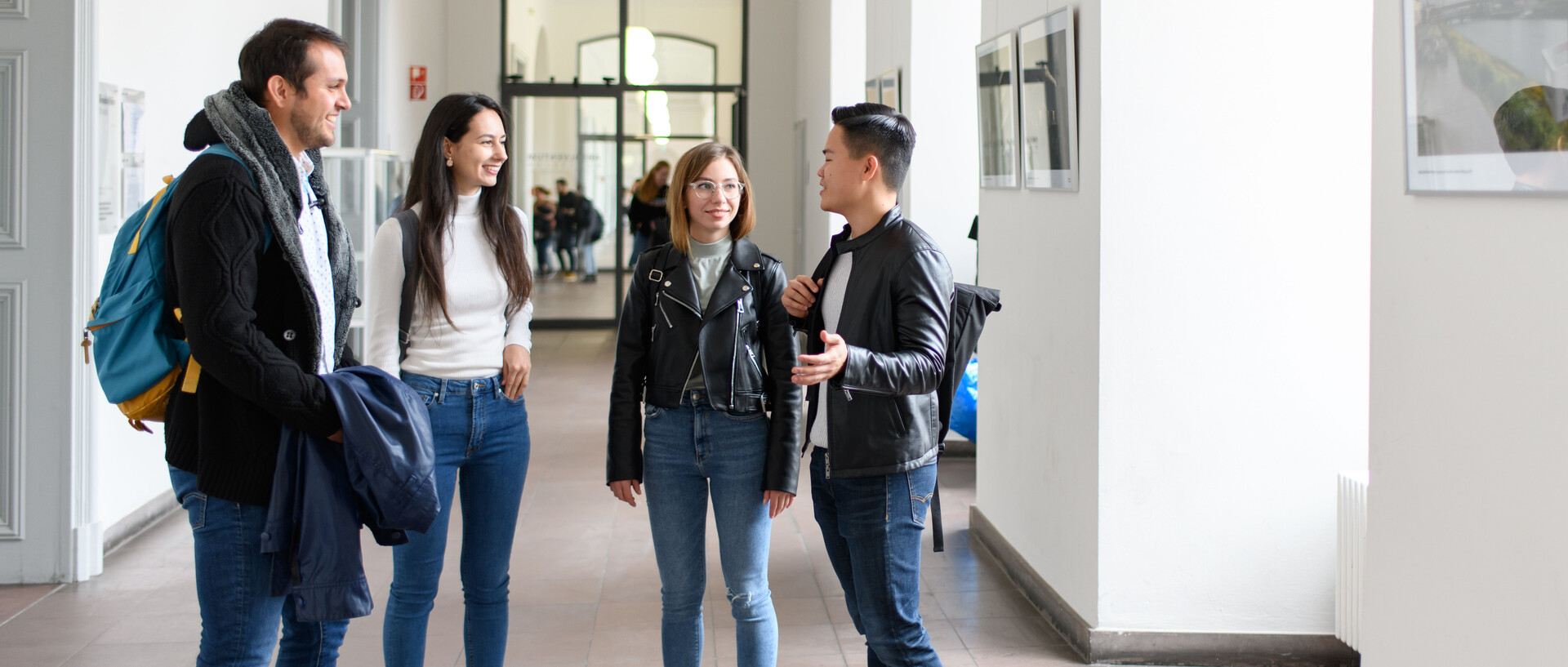 Studierende stehen im lichtdurchfluteten Flur des Barockschlosses und unterhalten sich. Link: Informationen zur Masterbewerbung