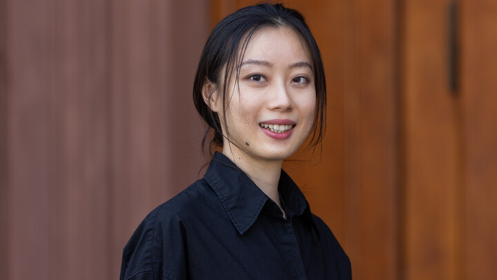 She is wearing a black blouse and standing in front of an entrance to Mannheim Palace.
