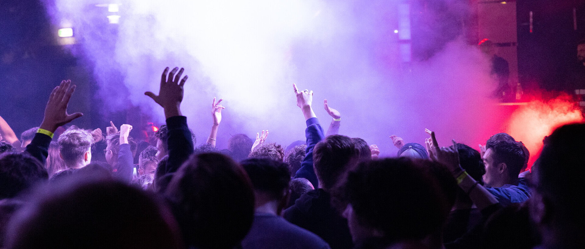 Menschen halten beim Feiern auf dem Schneckenhof ihre Hände in die Luft.