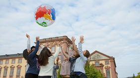 Bild von Studierenden die Ball mit Weltkarte hochwerfen