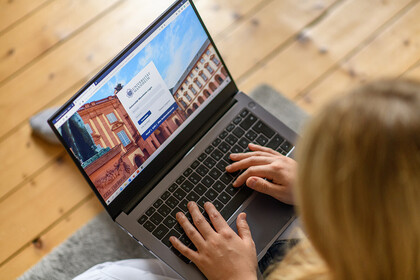Eine Frau loggt sich auf ihrem Laptop bei einer Webseite ein.