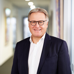 Stefan Fuchs hat kurze Haare, trägt eine Brille und lächelt freundlich.