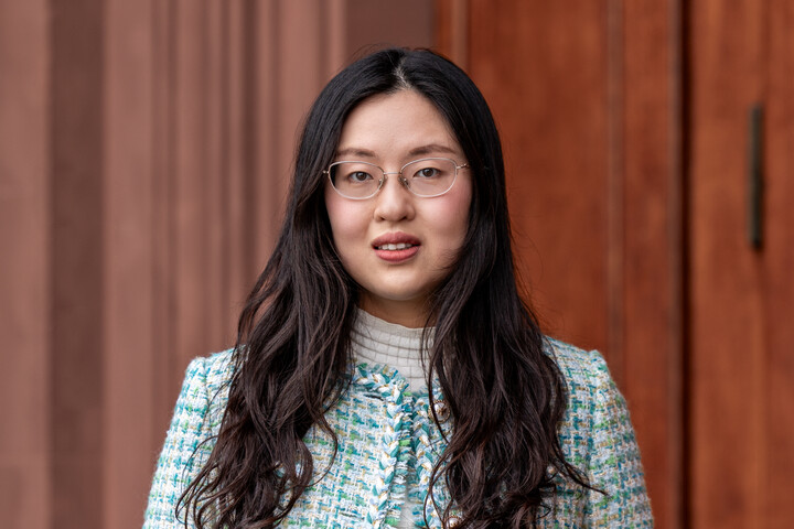 Portrait of Yin Yiwei. She is wearing a green/blue/white checked jacket and is standing in front of a door of Mannheim Palace.