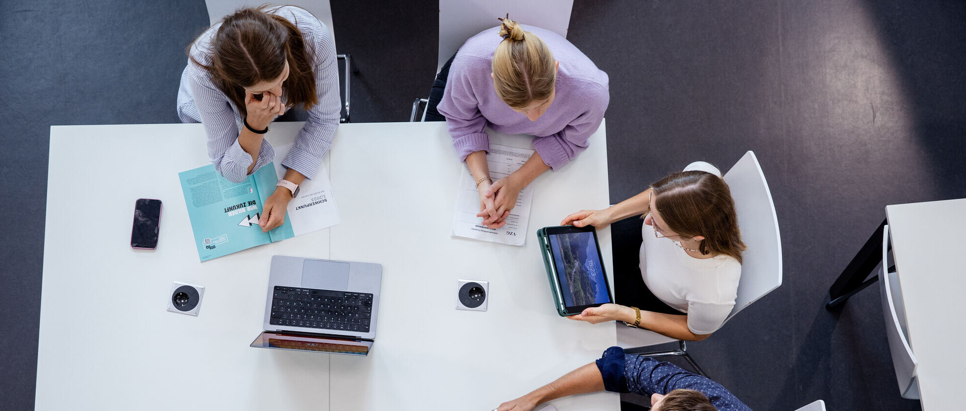 Vier Forschende an der Uni Mannheim sitzen an einem Tisch mit Laptops und Tablets.