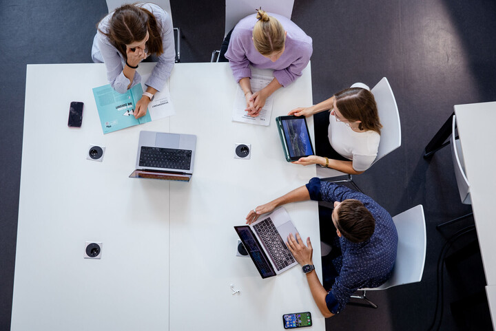 Vier Forschende an der Uni Mannheim sitzen an einem Tisch mit Laptops und Tablets.