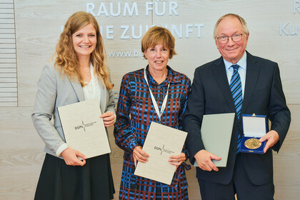 Die ausgezeichneten Personen stehen nebeneinander und halten Urkunden in der Hand
