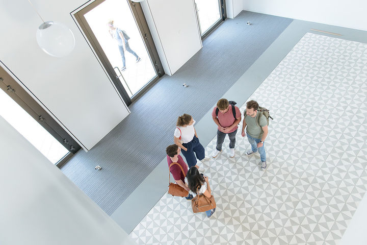 A group of students are talking in the entrance hall of B6, 30-32.