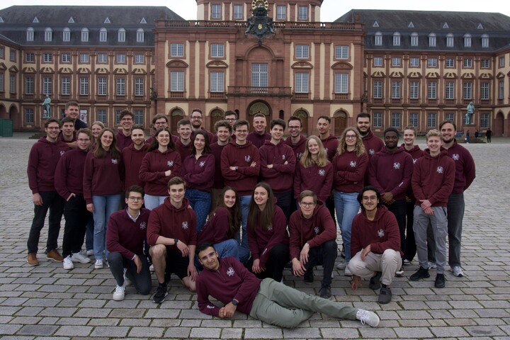 Ca. 30 Mitglieder der Fachschaft VWL stehen auf dem Ehrenhof für ein Gruppenfoto. Sie tragen alle einen weinroten Hoodie.