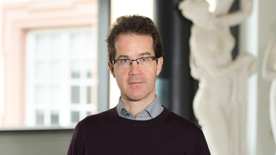Prof. Dr. Christian Mann hat kurze braune Haare und eine Brille. Er trägt einen braunen Wollpullover.