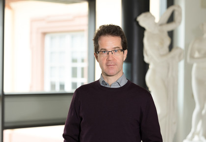 Prof. Dr. Christian Mann hat kurze braune Haare und eine Brille. Er trägt einen braunen Wollpullover.