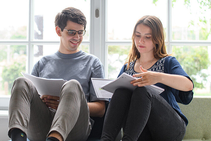 Zwei Studierende sitzen an einem Fenster und lernen gemeinsam.