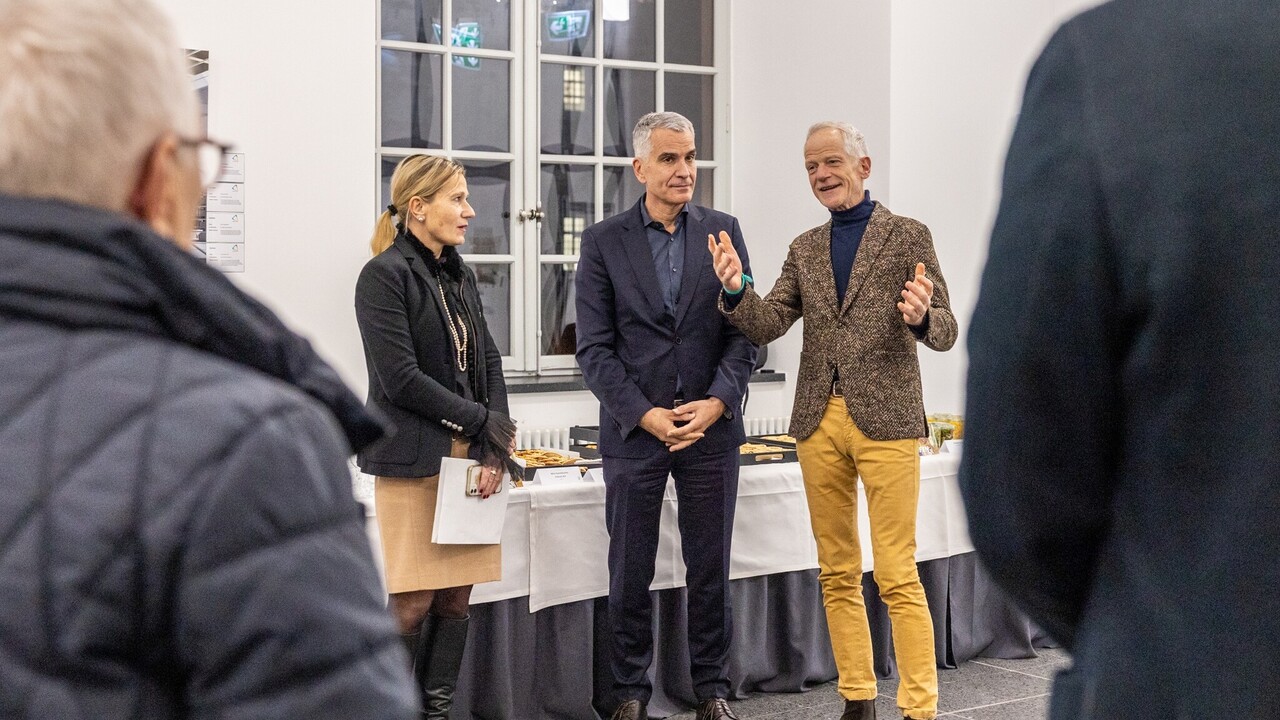 Thomas Fetzer steht mit zwei weiteren Personen vor einem Buffet bei der Spitzensport-Vernissage.