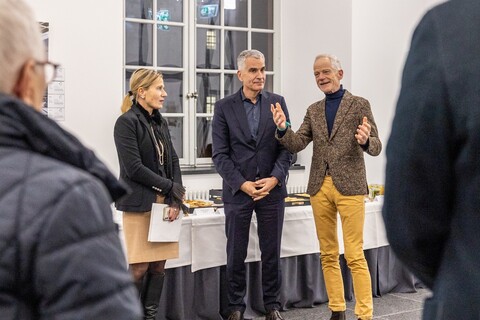 Thomas Fetzer steht mit zwei weiteren Personen vor einem Buffet bei der Spitzensport-Vernissage.