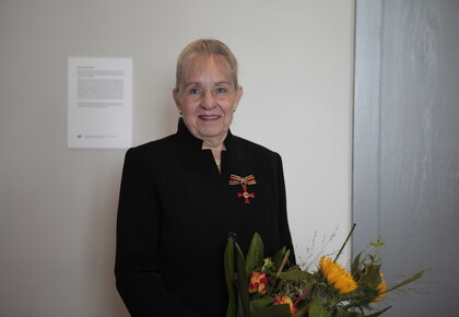 Dorothee Dickenberger steht vor einer Wand und hält einen Strauß Blumen in der Hand.
