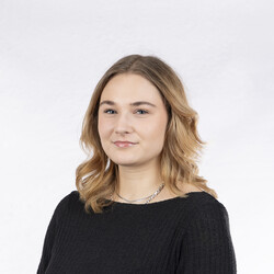 Lina Kramer trägt schulterlanges Haar und ein schwarzes Oberteil