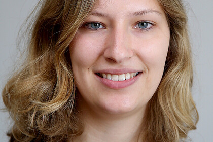 Laura Pohlan. She is standing in front of a grey wall.