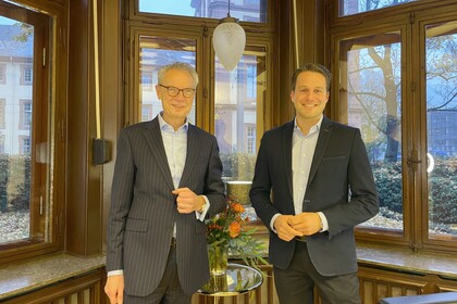 Prof. Glenk und Dekan Lutz stehen vor einer Fensterwand